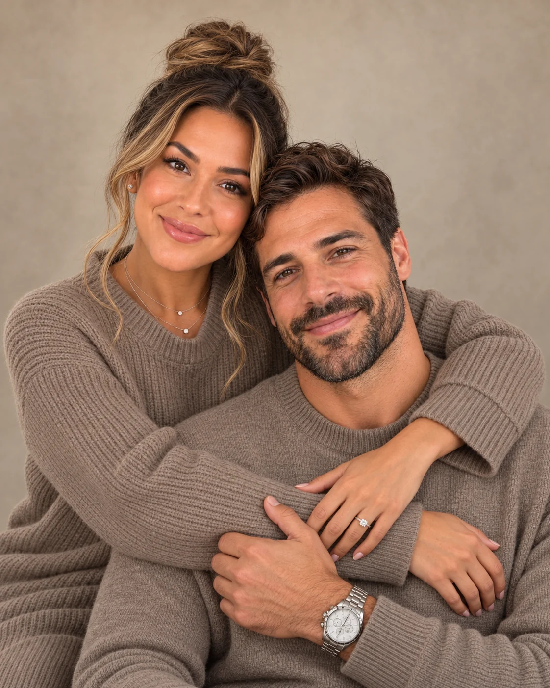 A close portrait of a couple embracing in matching taupe knitwear.