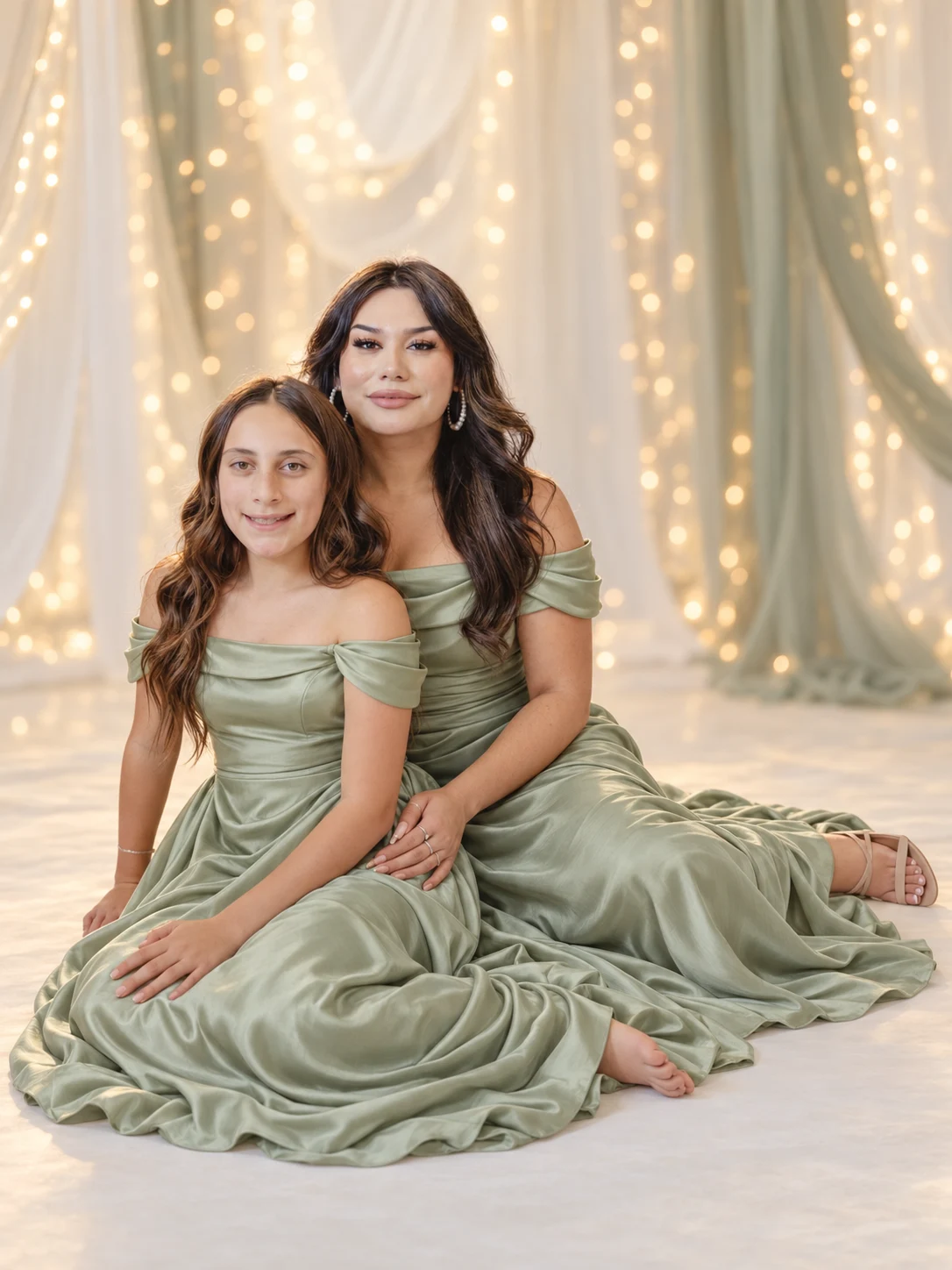 Mother and daughter in sage dresses beneath fairy lights